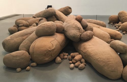 A full-room art exhibit of piles of sackcloth "pillows" that resemble potatoes, ranging from potato-sized to couch-sized.